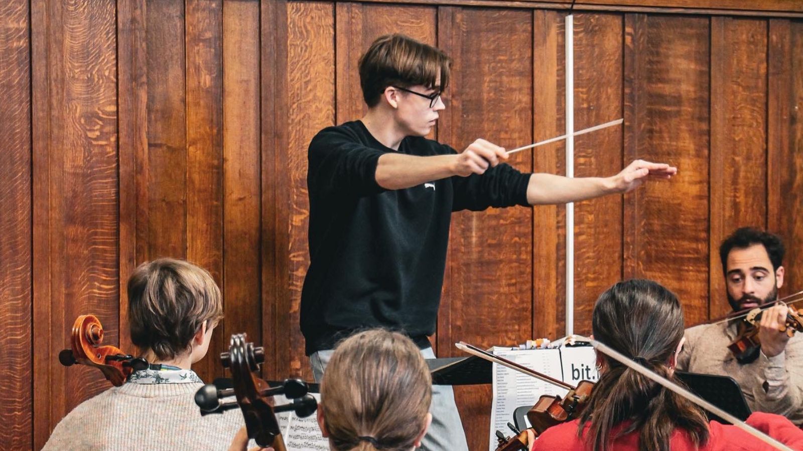 Felix Kirkby conducting a group of orchestral musicians