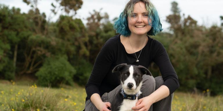 Photo of Edith Matthewson, who has shoulder length blue hair and her dog in a field