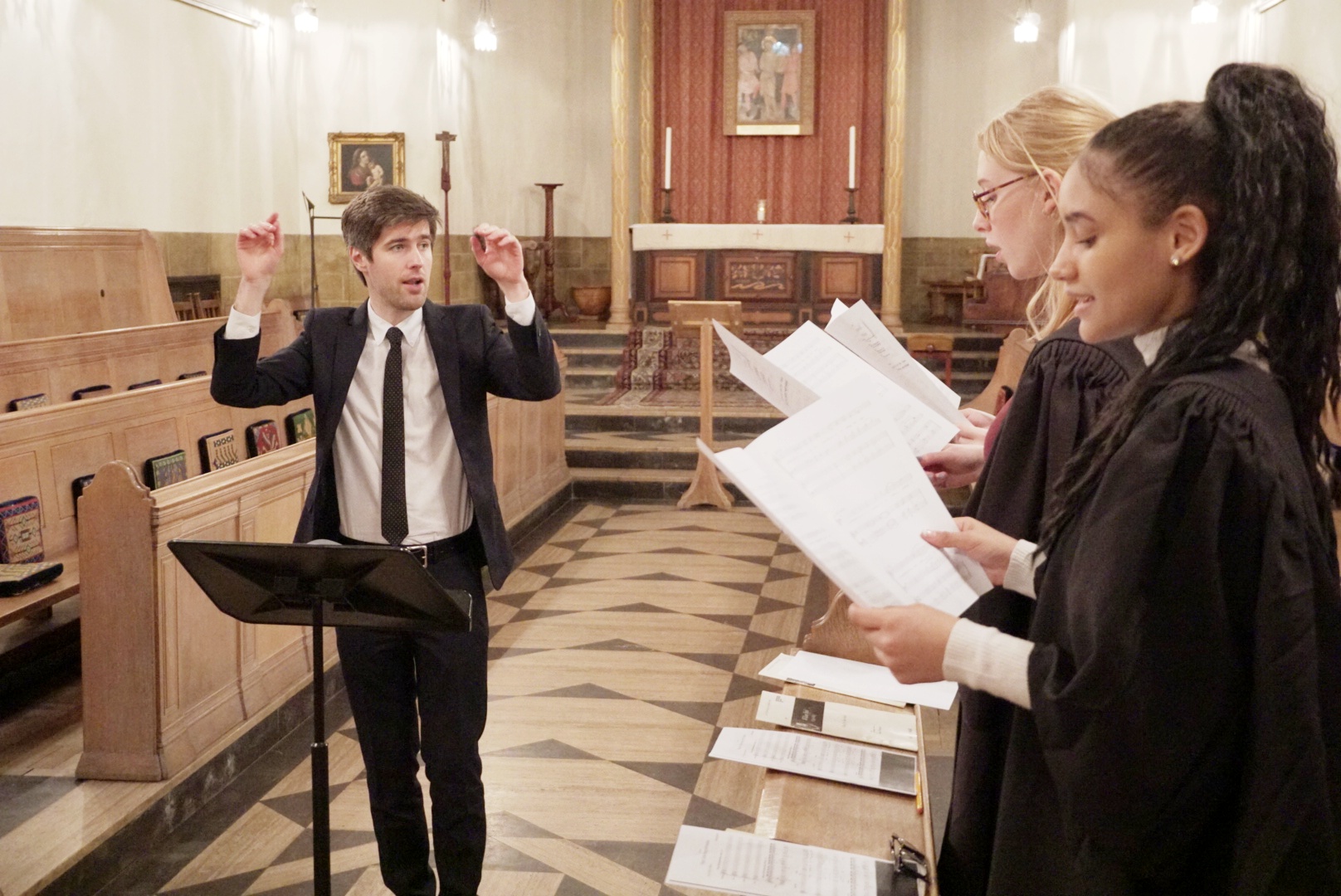 The Director of Chapel Music Paul Burke composing two students in the Chapel Choir inside the Chapel.
