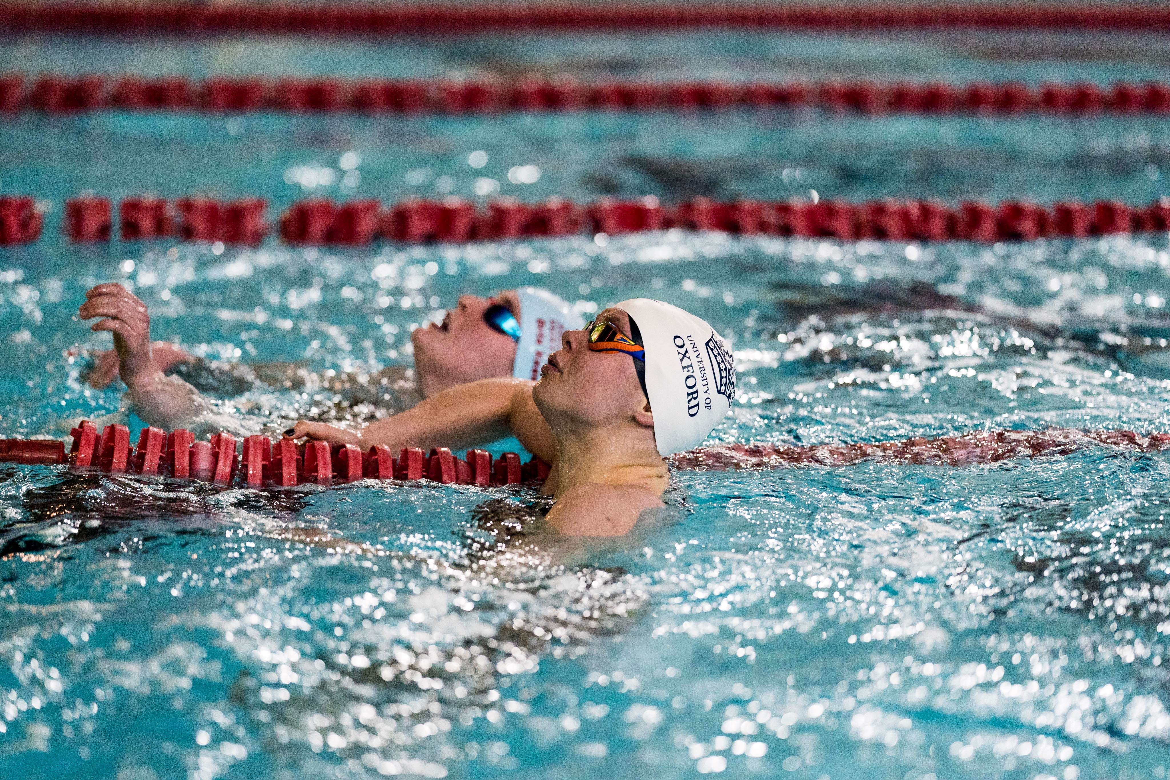 Two women wearing swimming caps in a swimming pool