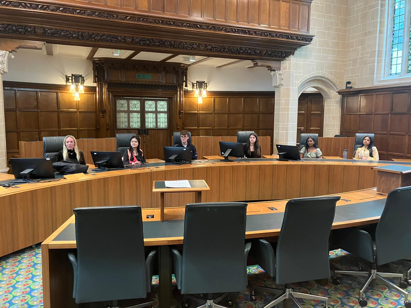 A photo of six students sitting at chairs at the UK High Court