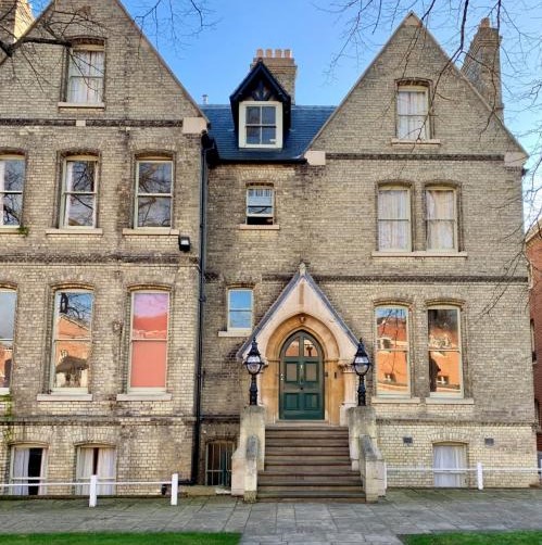 A three storey building in pale brick with steps leading up to the front door