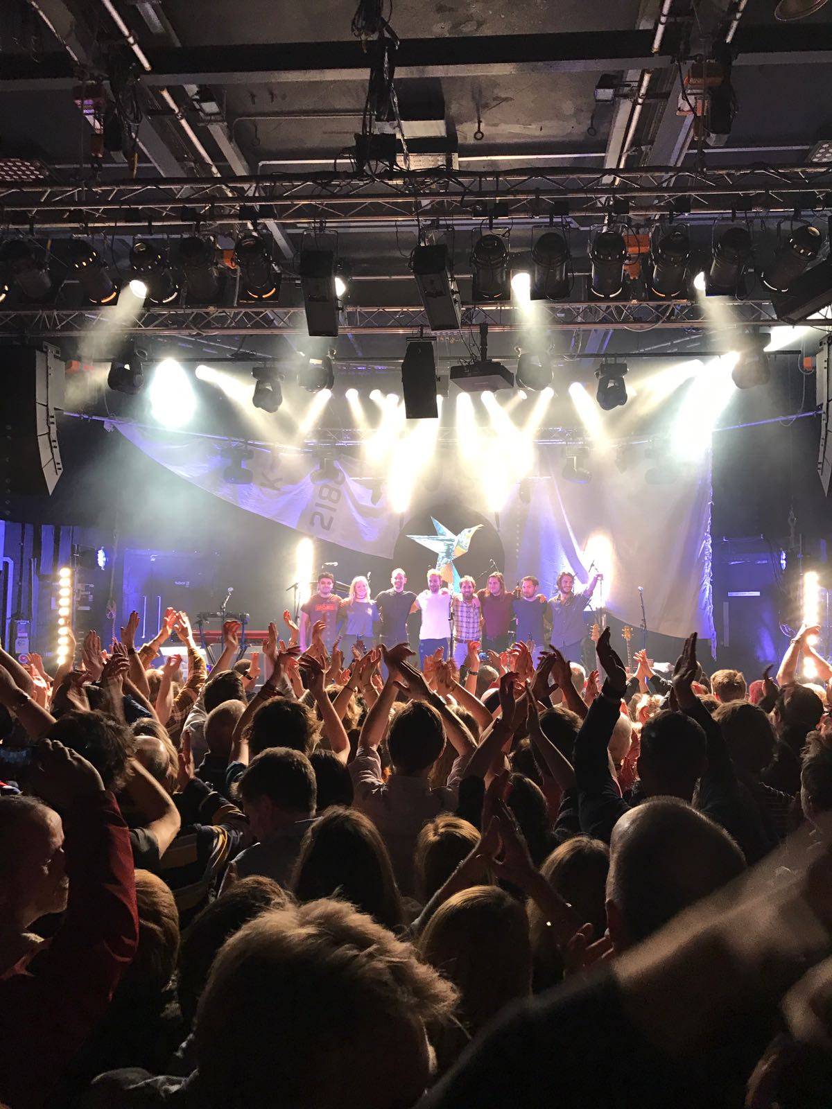 A crowd applauding the band on stage at a concert