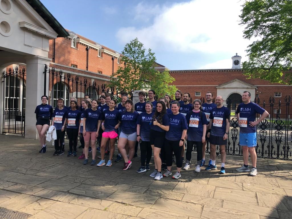 A group of people dressed in running clothes standing outside the gates of Lady Margaret Hall