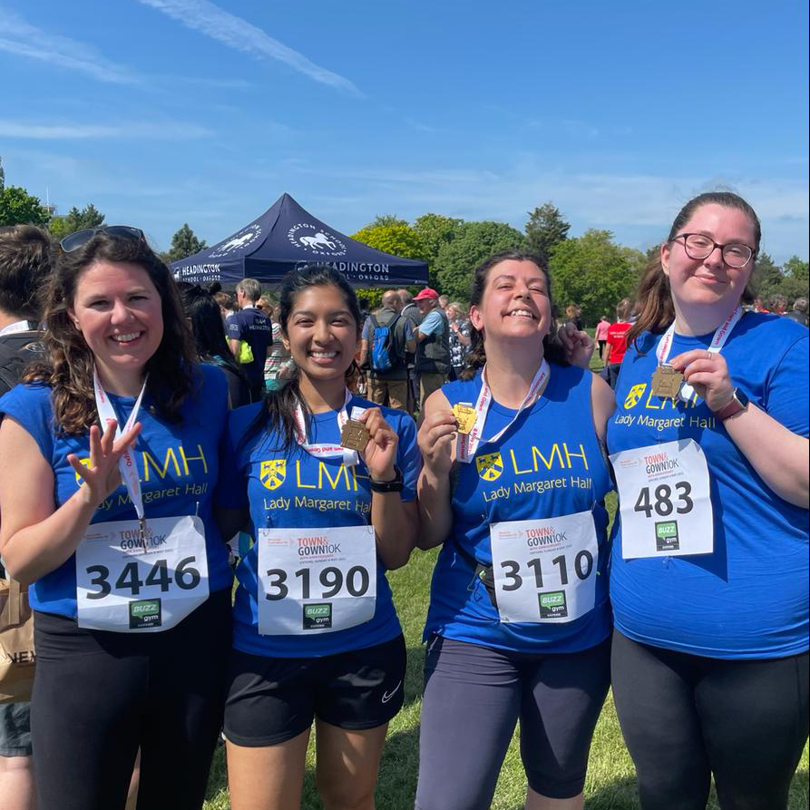 Four LMH runners holding medals after completing Town and Gown charity run