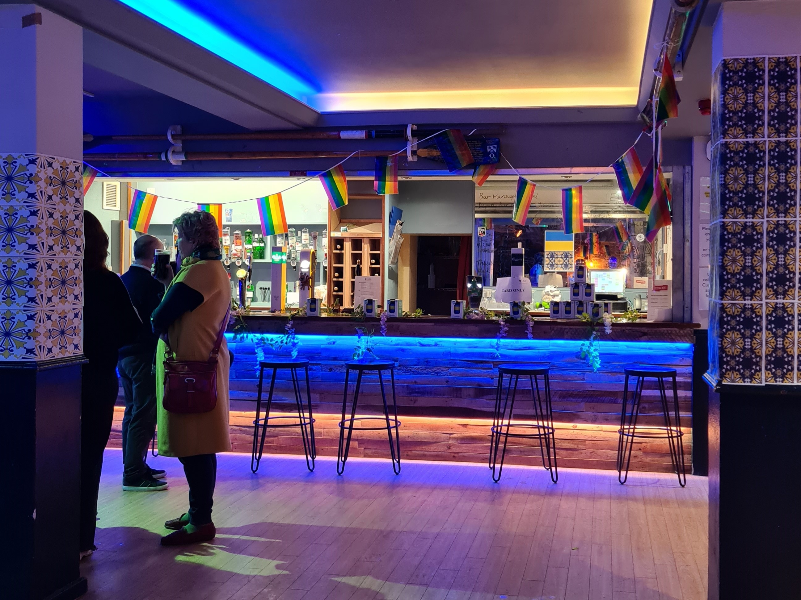 Photo of people standing in a bar with blue lighting
