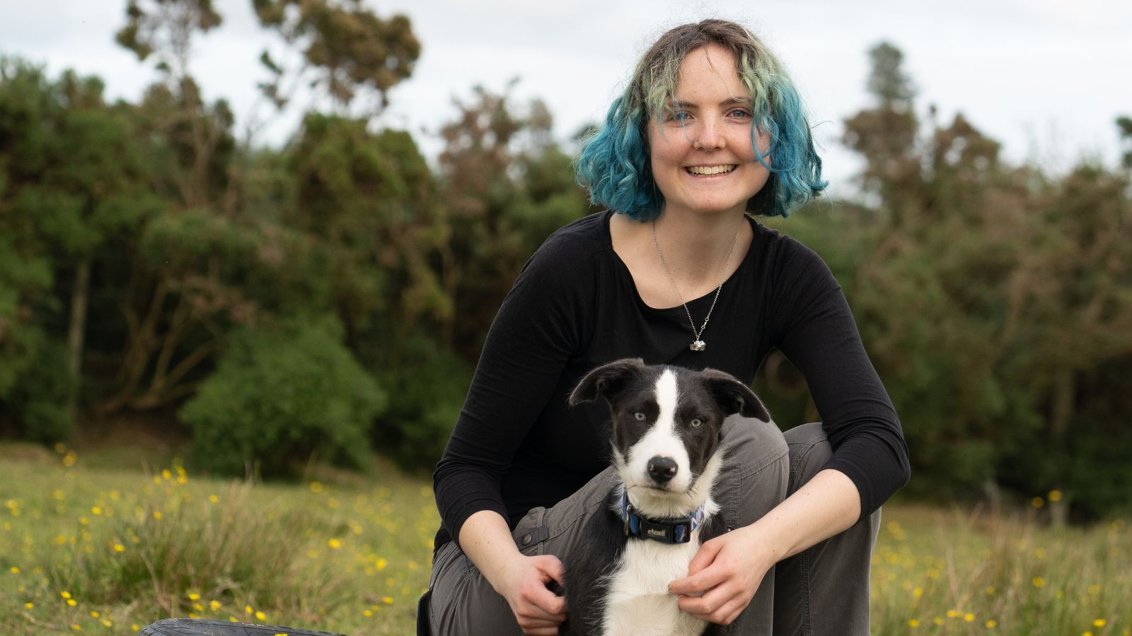 Photo of Edith Matthewson, who has shoulder length blue hair and her dog in a field