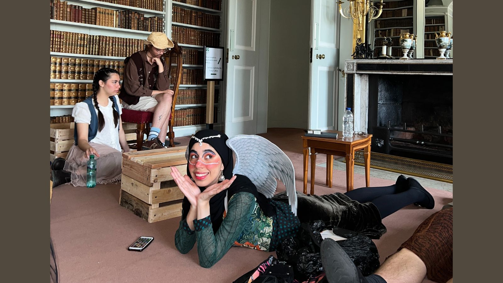 Students in costume relax while preparing for a performance of their play in a large stately home