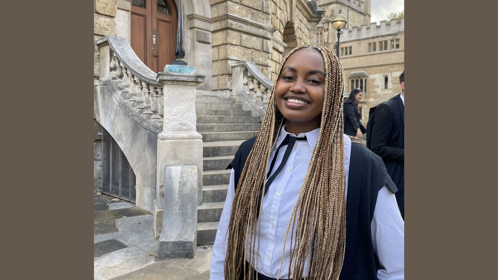 Lynnie Ngũgĩ, a young Black woman with long blonde and brown braids wearing Oxford academic dress