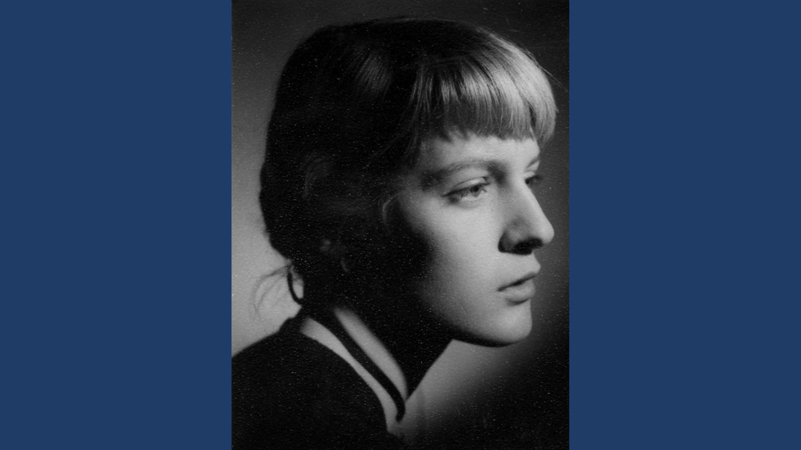 A black and white portrait photo of a young woman with tied-back blonde hair and a fringe
