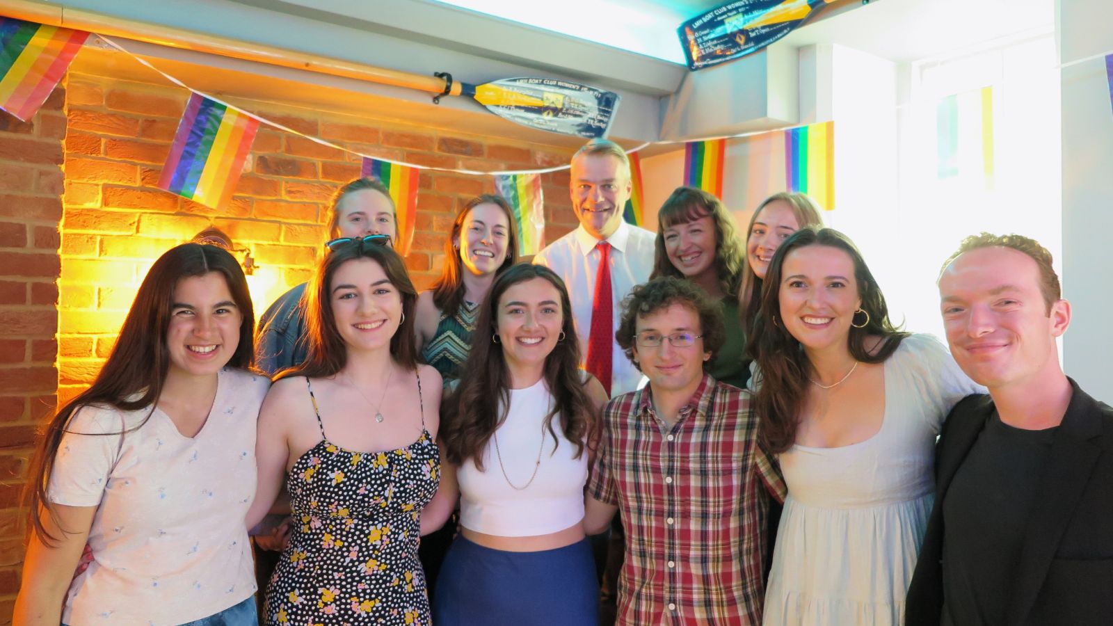 A photo of a group of students standing underneath rainbow banners