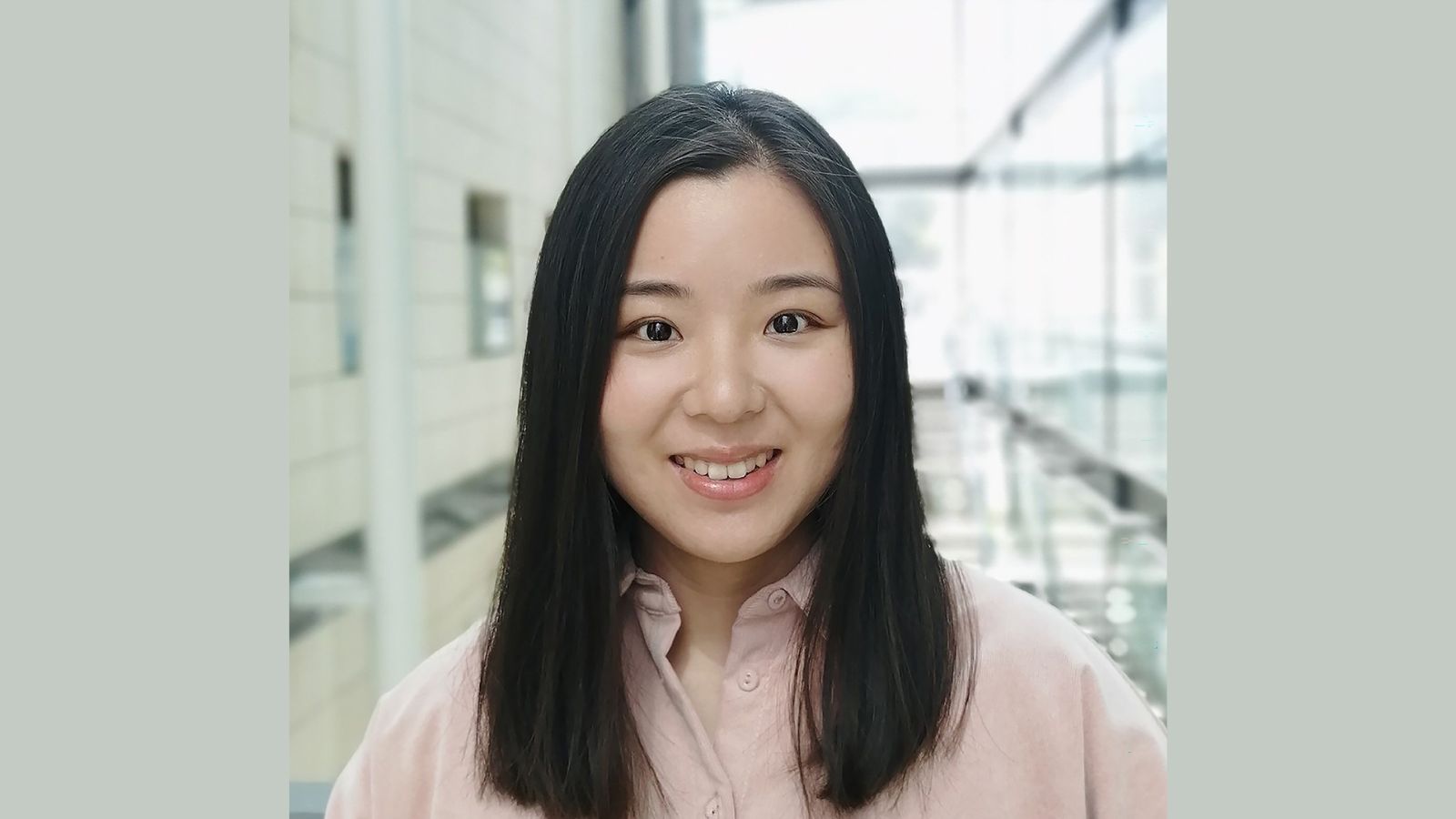 Yujia Qing standing in a brightly lit atrium