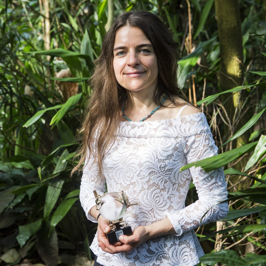 Geraldine Werhahn smiles at camera, standing against foliage