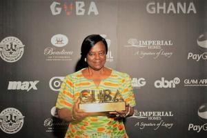 A picture of Charlotte Boaitey holding a golden award statue that reads CUBA.