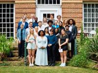 A group of young people from the LMH foundation year gather on some steps in the gardens