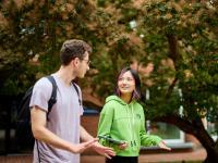 A male student and a female student walking outside talking to one another