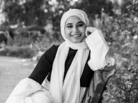 Black and white photo of Sharifah Alihinai sitting on a bench under a tree