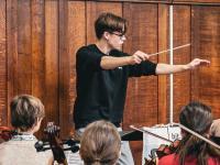 Felix Kirkby conducting a group of orchestral musicians