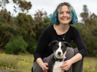 Photo of Edith Matthewson, who has shoulder length blue hair and her dog in a field