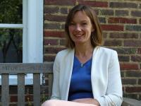 Anna Bates, a white woman with shoulder-length brown hair wearing a white jacket