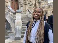 Lynnie Ngũgĩ, a young Black woman with long blonde and brown braids wearing Oxford academic dress