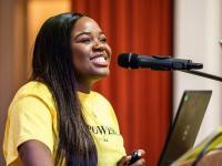 A close up photo of Vee Kathivu, wearing a bright yellow Empowered by Vee t-shirt