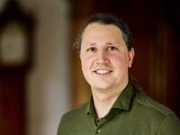 Photo of Dr Balint Koczor, who has long hair pulled back in a ponytail