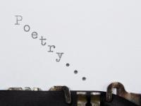 Close up of a piece of paper in a typewriter - the word 'poetry' is spelled out