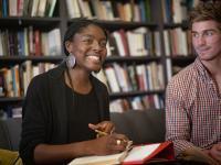 Two students enjoying a tutorial with a bookshelf in the background