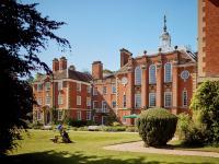 A shot of a red brick building set in beautiful gardens