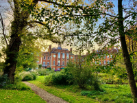 A photo of a red brick building peeping out through some trees