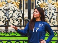 Tara with a volleyball standing outside All Souls College gates