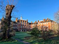 The gardens of Lady Margaret Hall in the winter. A red brick building with a bright blue sky in the background