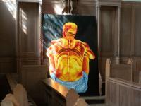 Grace Steinberg's vivid painting of a man's back on a black background, with light from the stained glass windows pouring over it 