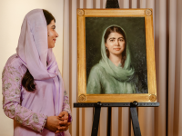 Malala Yousafzai, wearing a lavender purple outfit and headscarf, looks across at an oil portrait of herself