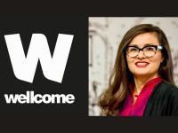 A headshot of Professor Ana Domingos, a woman with long dark brown hair who wears glasses and a pink top alongside the Wellcome Trust logo