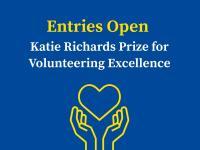 Blue background with graphic of a pair of hands holding up a heart. Text reads: Entries Open for Katie Richards Prize for Volunteering Excellence