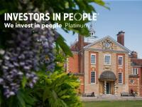 A photo of a red brick building with wisteria in the foreground, overlaid with the Investors in People Platinum logo