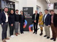 A group of men and women stand in a line. Between them a banner reads 'Cancer Grand Challenges: Dare to think differently'