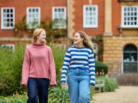 Two female students having a conversation while walking through the LMH grounds