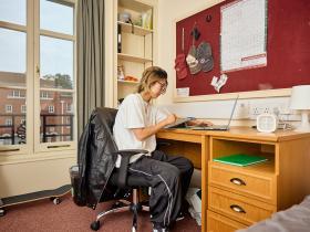 A student sitting at a desk in her student accommodation