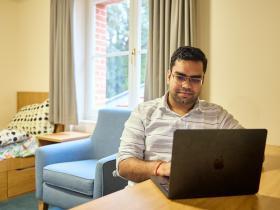 A male student sitting at a desk with a laptop