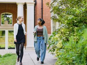 Two female students walking and chatting in the LMH gardens