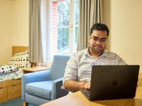 A male graduate student sitting in their student accommodation