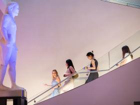 Three LMH students walking down a staircase in the Ashmolean Museum near an Egyptian statue