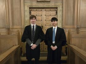 Two young men wearing black gowns stand in the LMH college Chapel