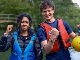 Two students in life jackets looking towards the camera on land after canoeing