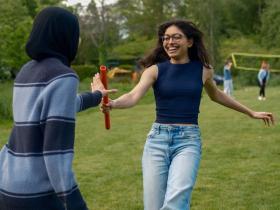 Two students, one passing a relay baton to the other