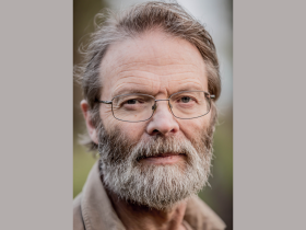 Professor David Macdonald, who has short greying hair and a grey beard, looks directly into the camera