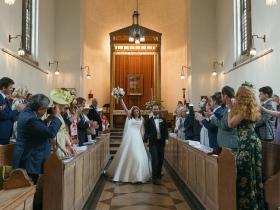 A wedding taking place in the LMH Chapel, with guests cheering for the happy couple as they walk down the aisle